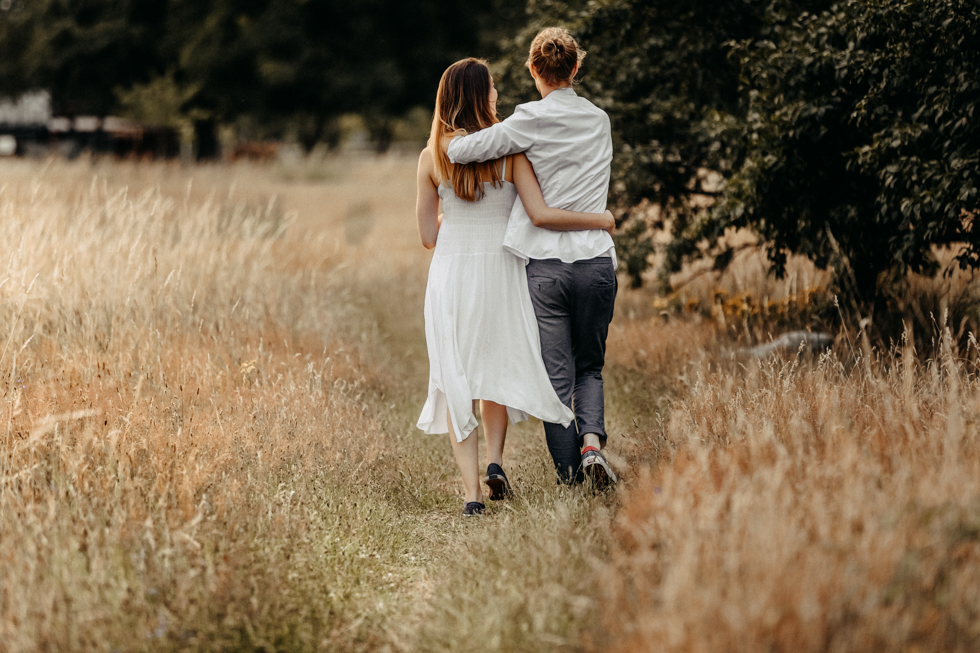 Paar läuft Arm in Arm durchs hohe Gras