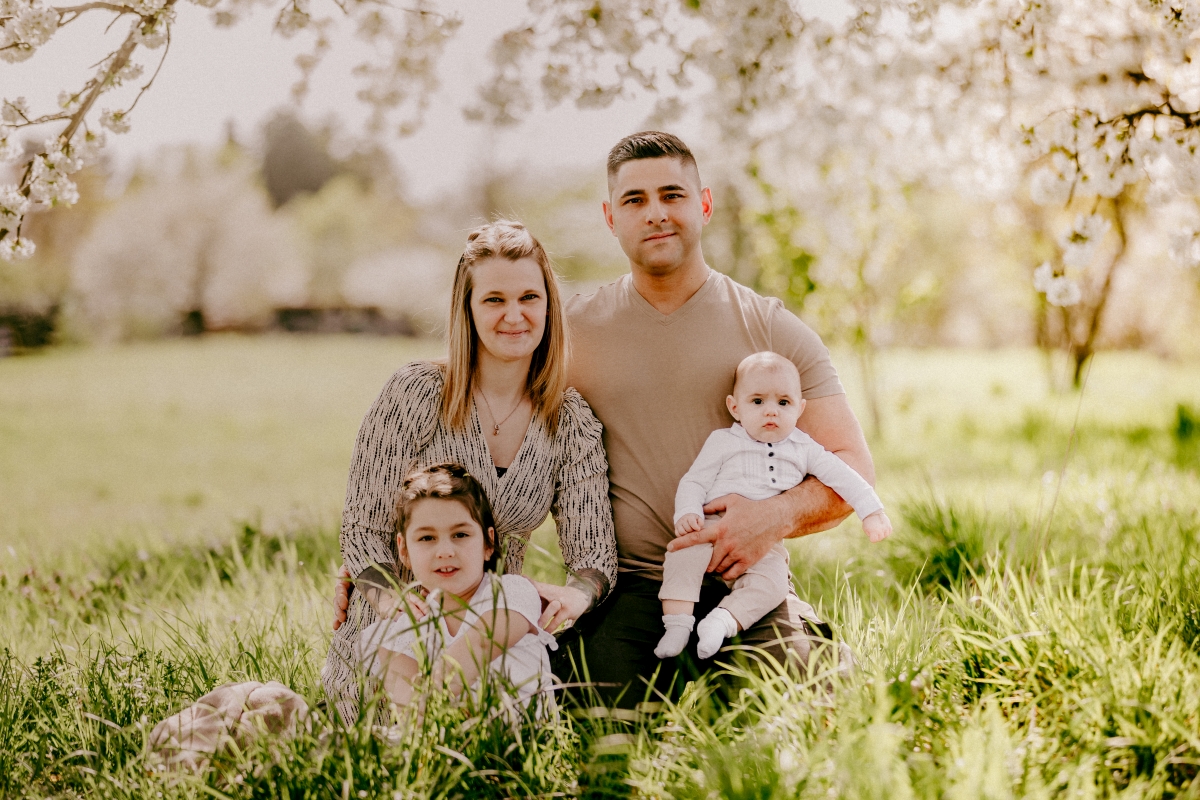 Familie mit Baby und Mädchen im Frühling unter Kirschblüten beim Familien-Fotoshooting