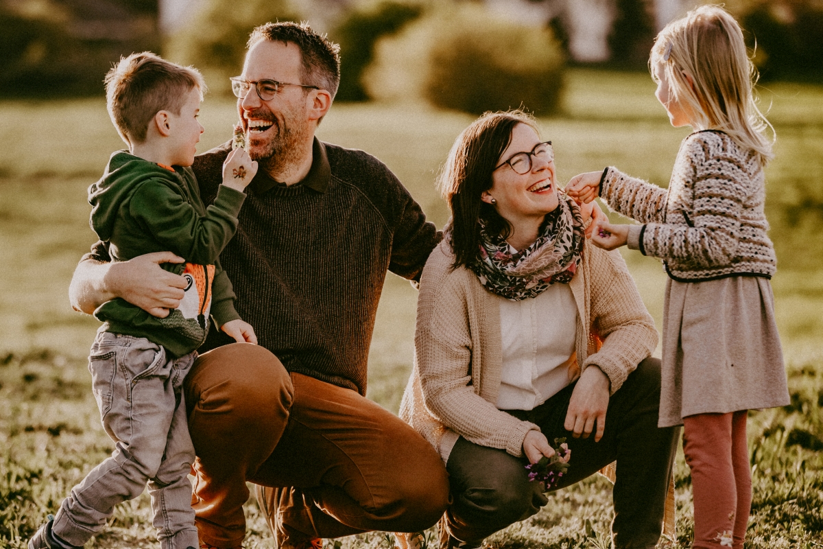 Familie lachend im Sonnenuntergang in der Natur beim Familien-Foto-Shoot