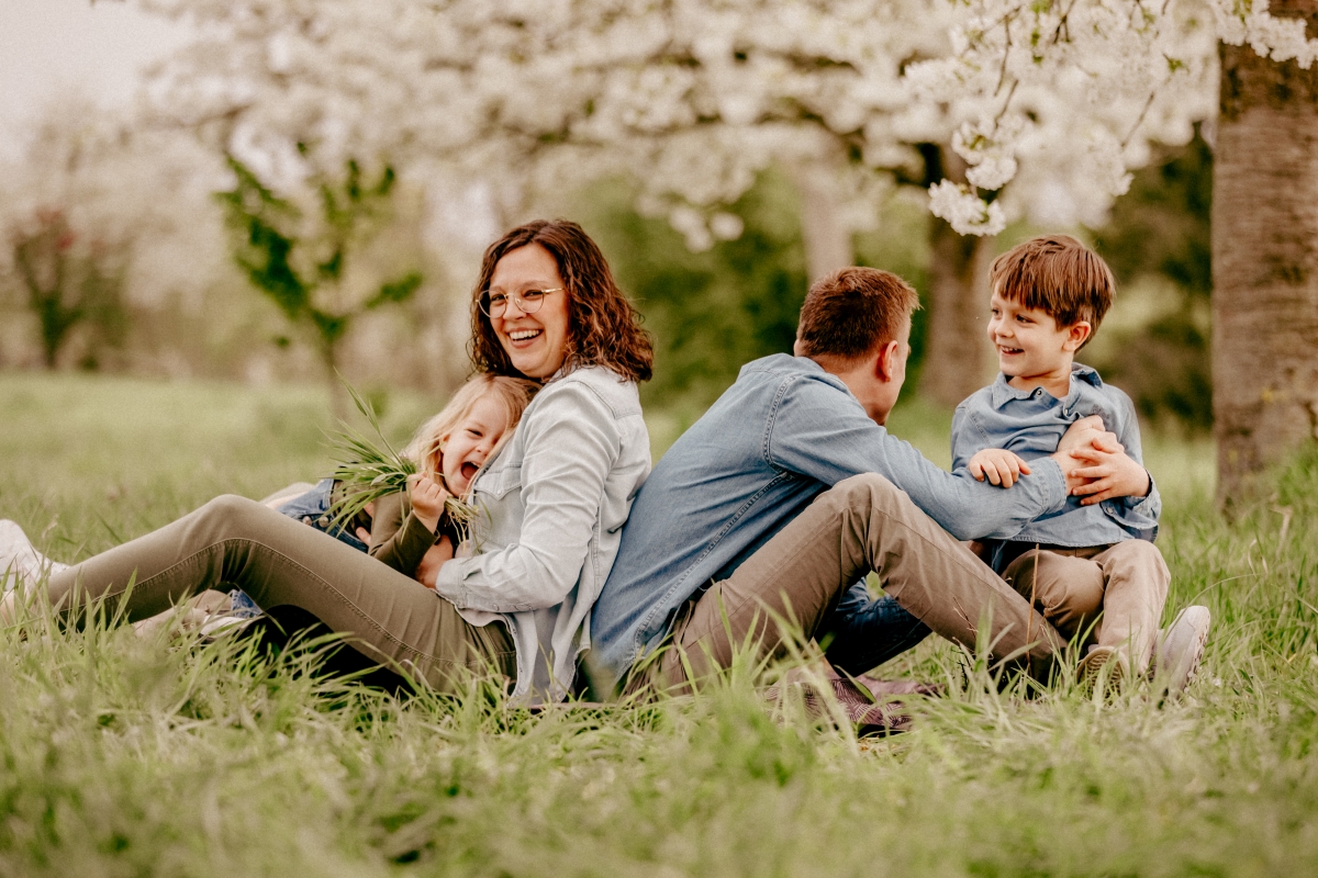 Familie kuschelt unter Kirschblüten beim Familien-Fotoshooting