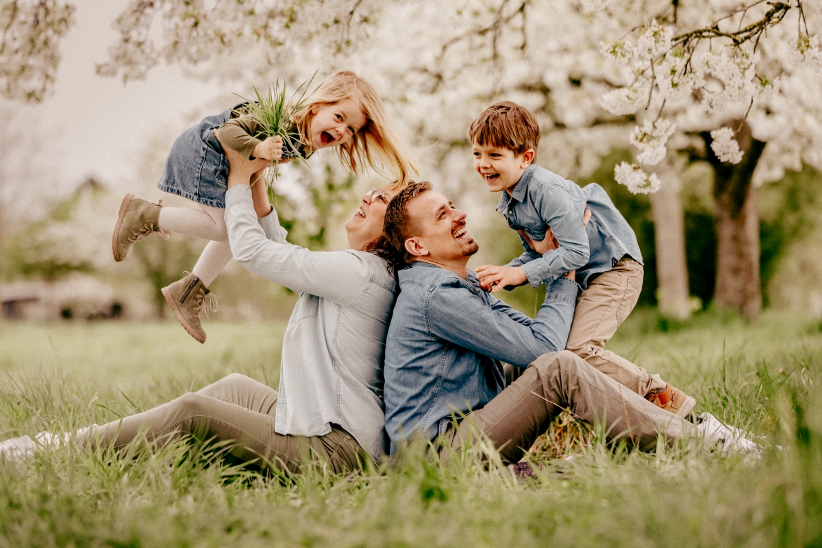Familie kuschelt unter Kirschblüten beim Familien-Fotoshooting