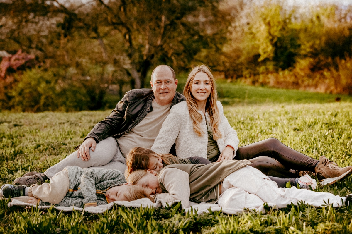 Familie mit drei Kindern auf Decke liegend beim Foto-Shooting im Sonnenuntergang