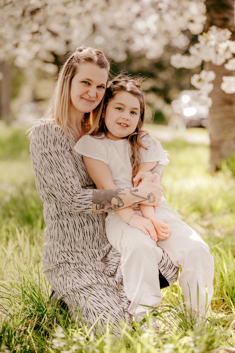 Mama und Tochter im Frühling unter Kirschblüten beim Familien-Fotoshooting