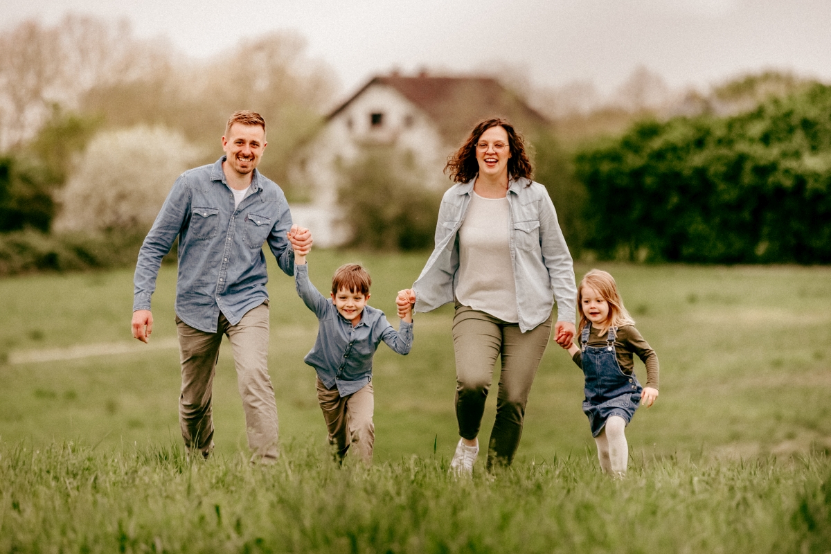 Familie läuft mit Kindern auf Frühlingswiese beim Familien-Fotoshooting