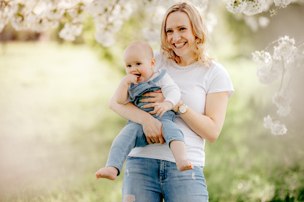 Mama mit Baby im Frühling unter Kirschblüten beim Familien-Fotoshooting