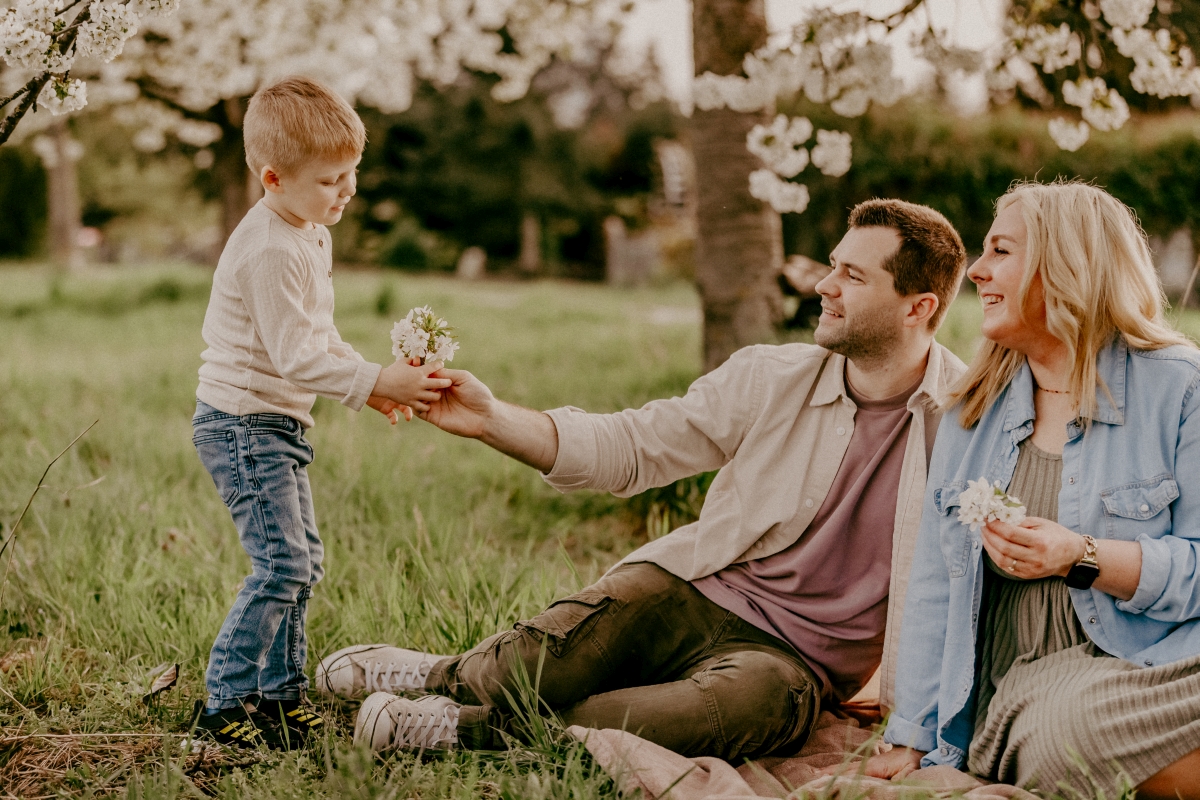 Eltern und Sohn unter Kirschblüten beim Familien-Fotoshooting