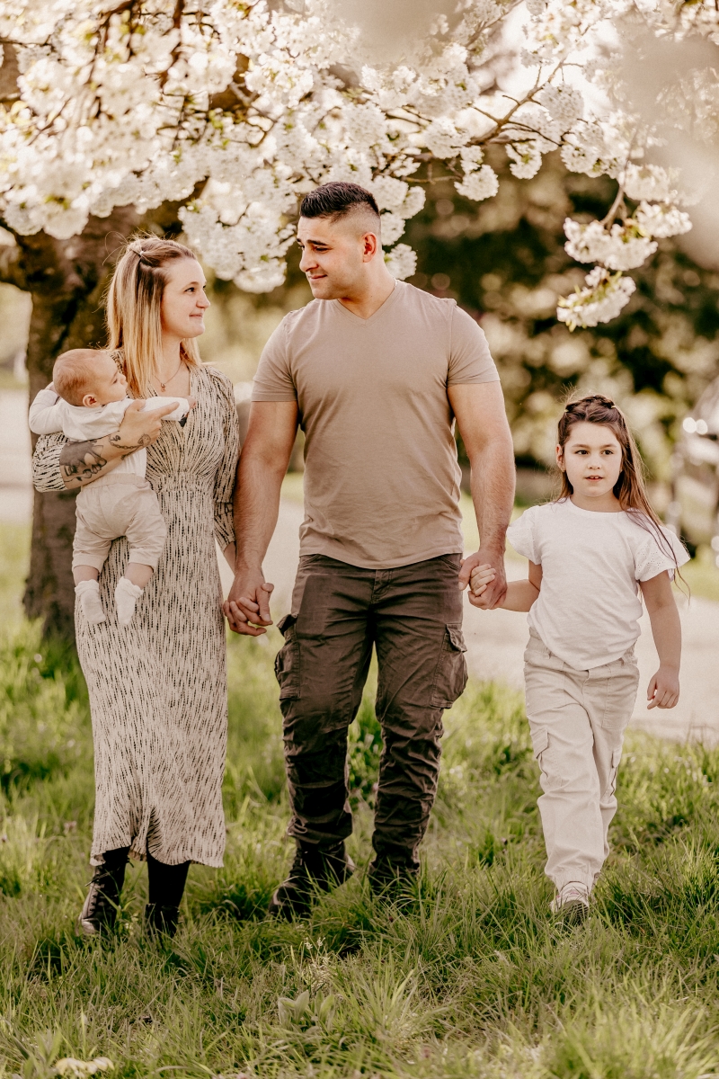 Mama und Papa mit Baby und Mädchen im Frühling unter Kirschblüten beim Familien-Fotoshooting