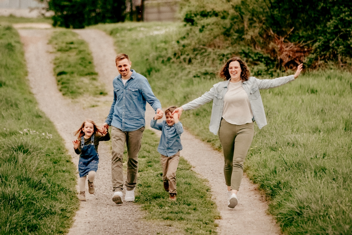 Familie rennt mit Kindern auf Frühlingswiese beim Familien-Fotoshooting