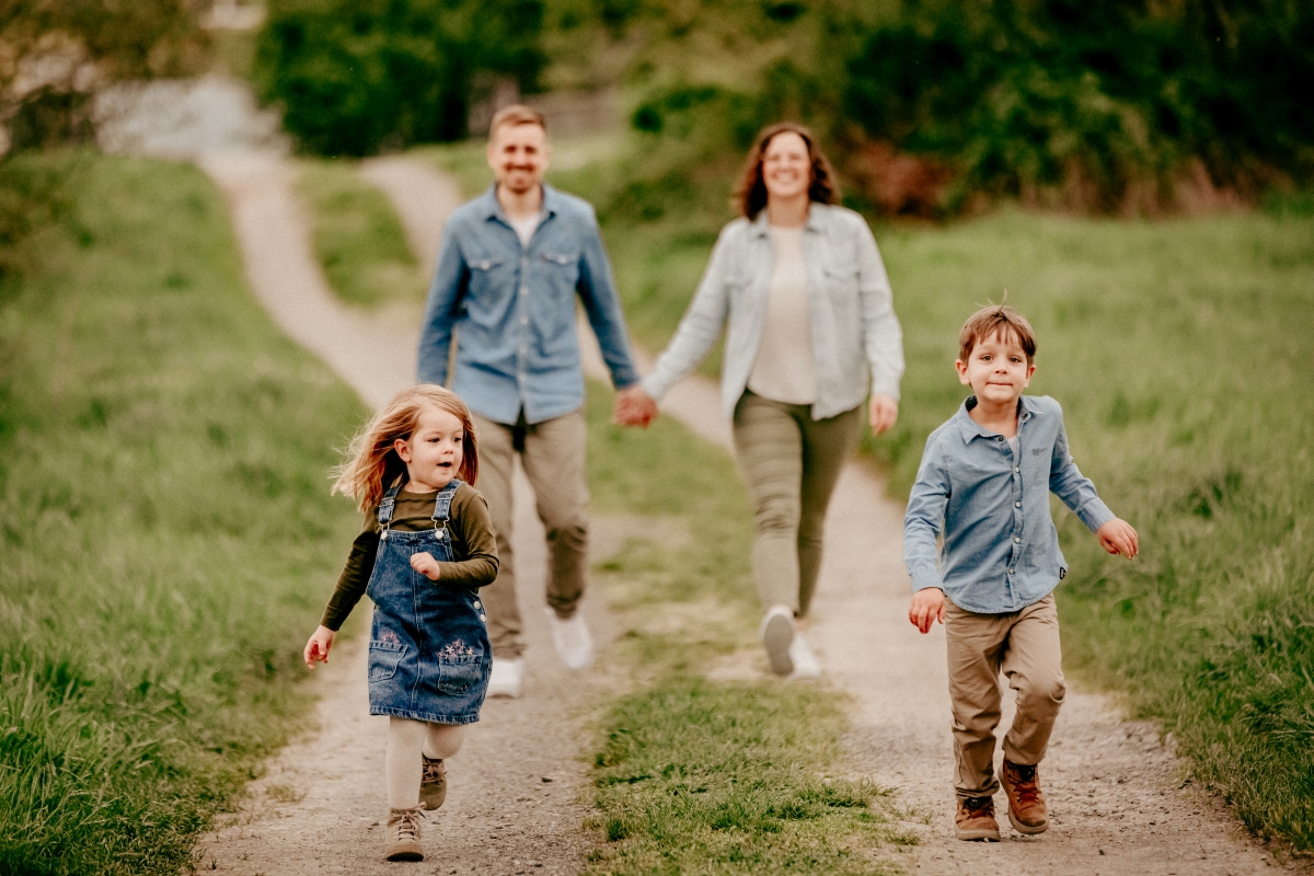 Familie rennt mit Kindern auf Frühlingswiese beim Familien-Fotoshooting