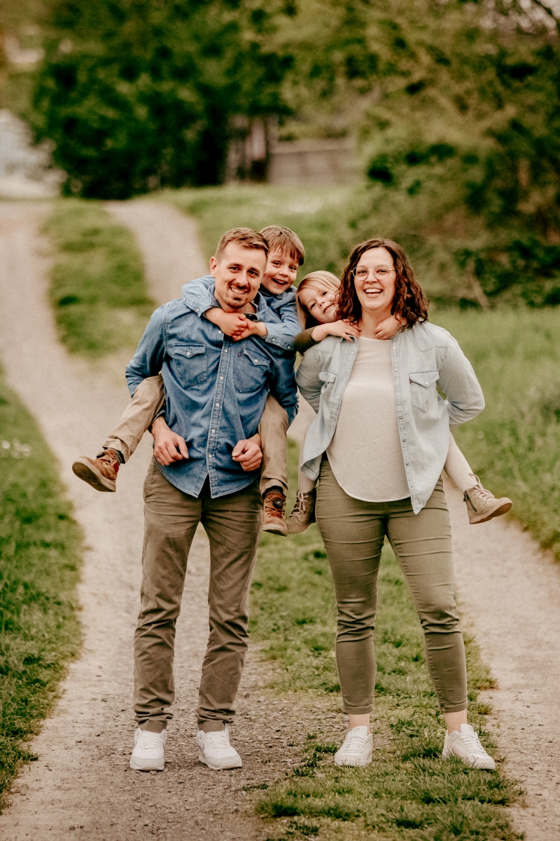 Familie mit Kindern Huckepack auf Frühlingswiese beim Familien-Fotoshooting