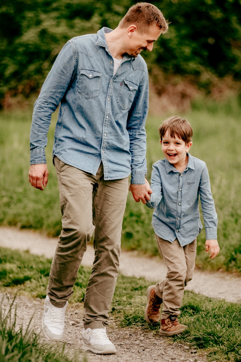 Papa und Sohn laufen über Frühlingswiese beim Familien-Fotoshooting