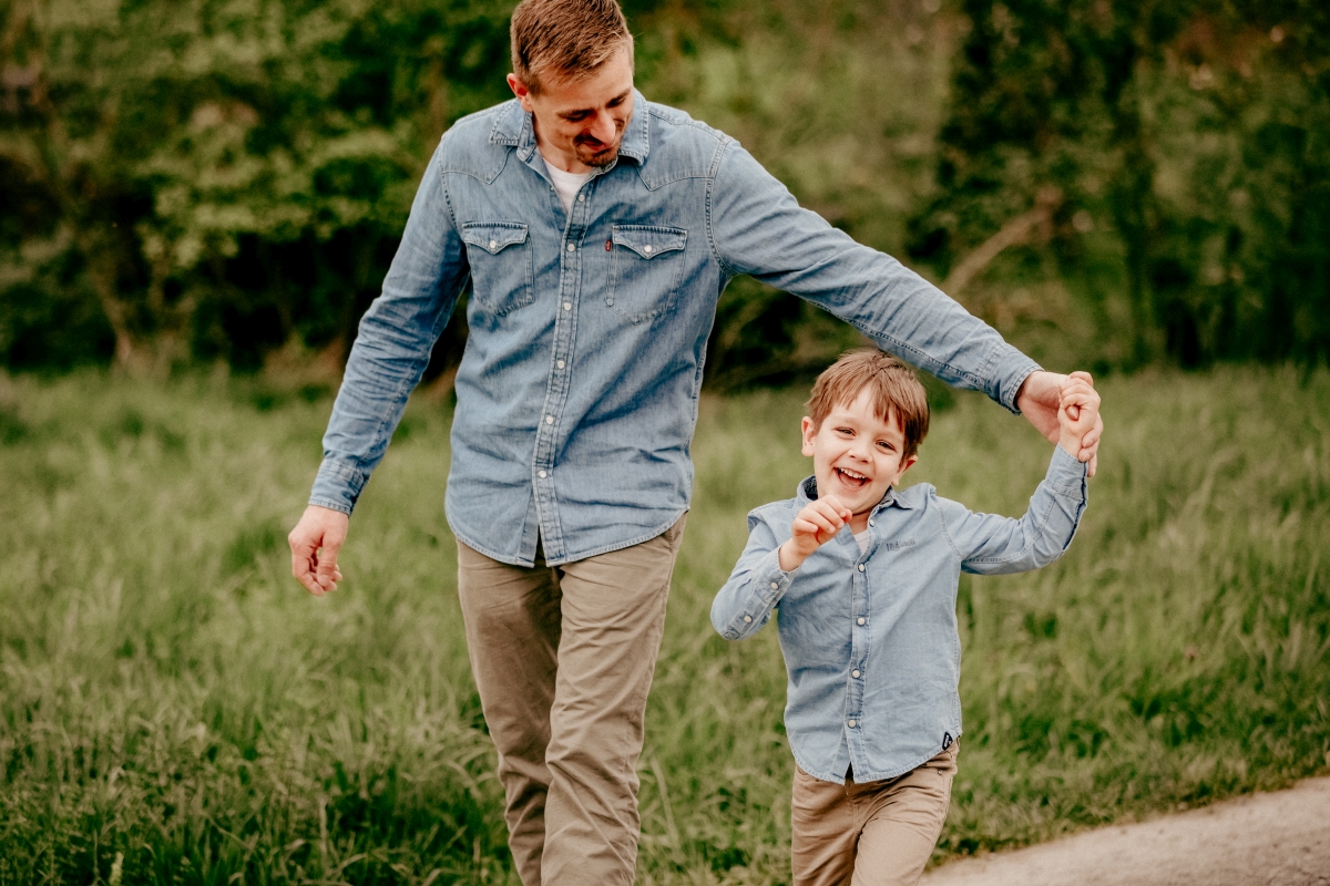 Papa und Sohn laufen über Frühlingswiese beim Familien-Fotoshooting